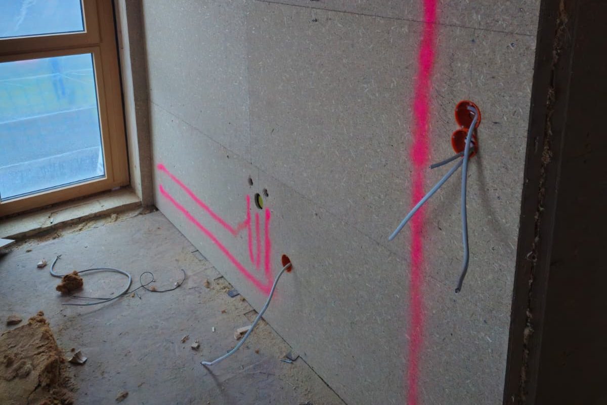 Rohinstallation mit pinken Markierungen und Kabeln an einer Wand.